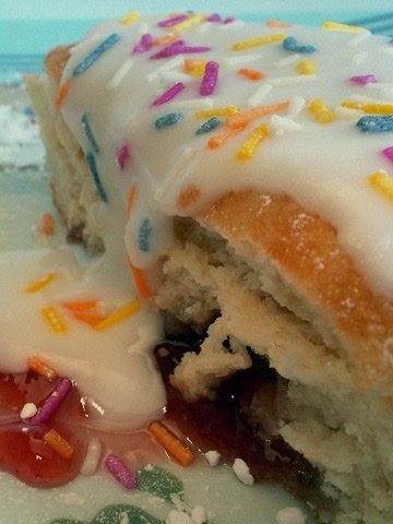 A super sweet and sticky looking pastry oozing with jelly and coasted with white icing and sprinkles, an example of food and sugar addictions